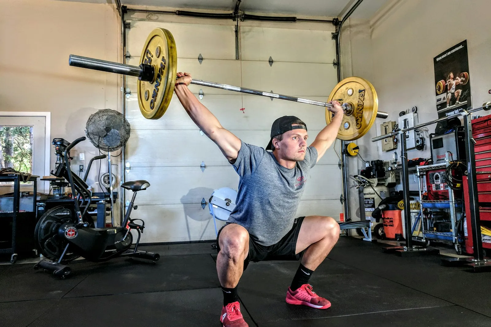 A person doing an overhead barbell press in a home garage gym