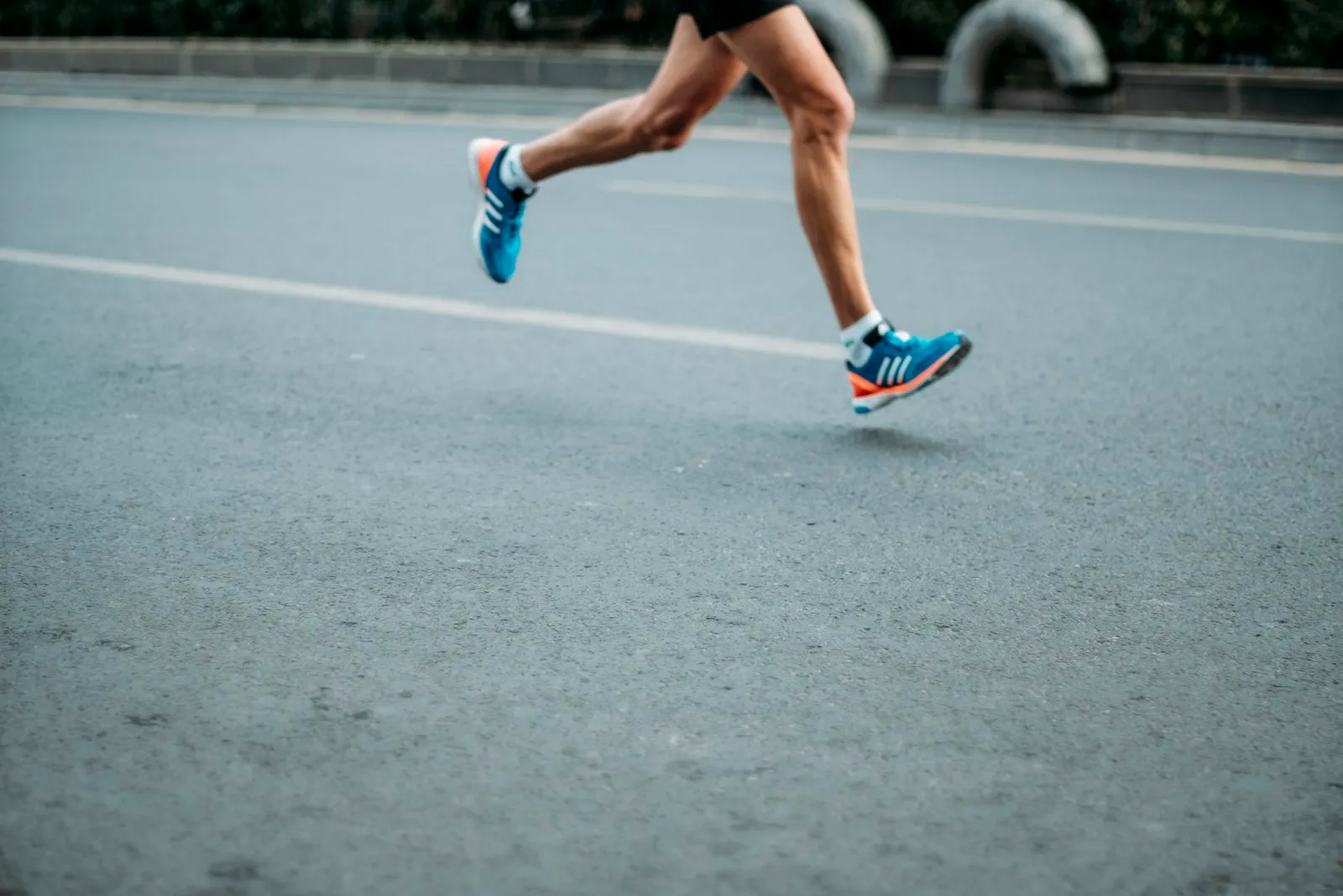 A runner mid-stride on an open road, captured from the waist down